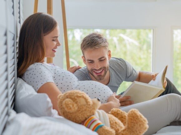 dad reading book to pregnant woman