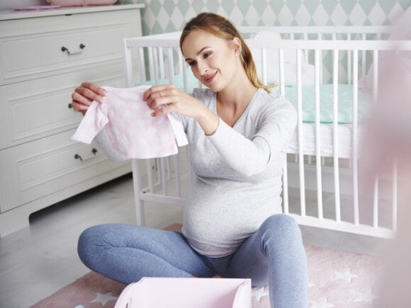 pregnant woman looking at newborn clothes