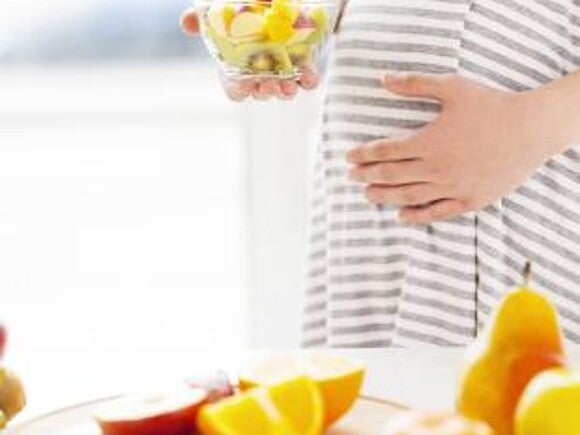 Pregnant woman with a bowl of fruit salad.