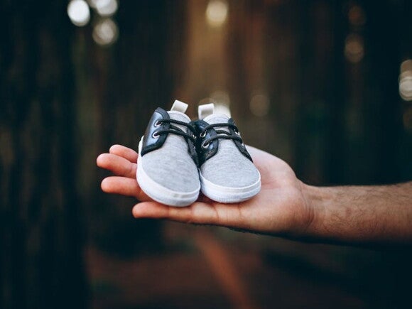 Man holding a pair of baby boots in a forest