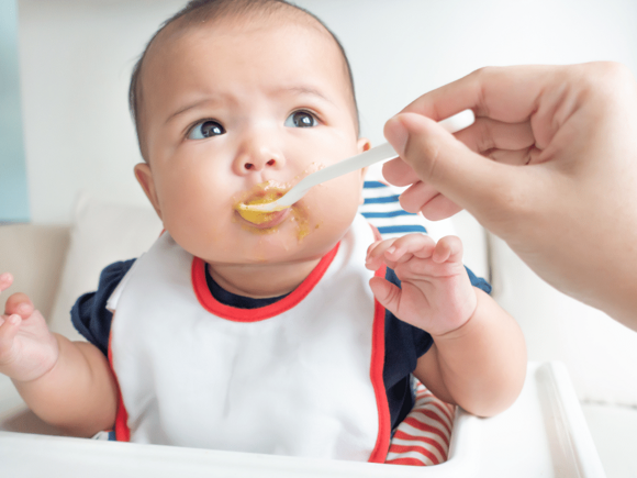baby eating puree fed by parent