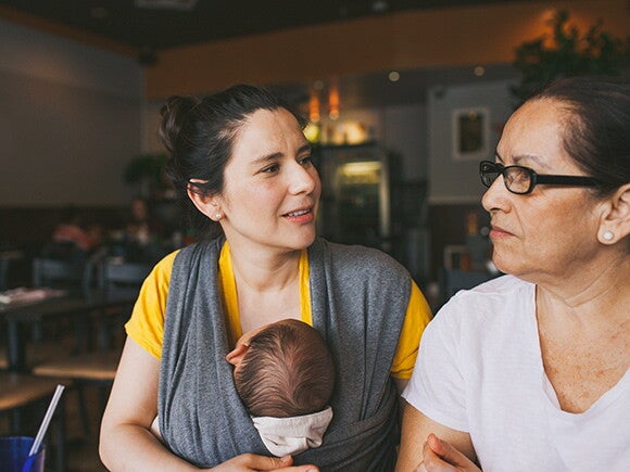 Woman with baby in carrier talking to an older woman