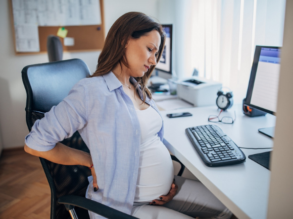Pregnant woman with back pain at desk