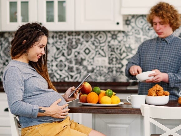 Pregnant woman looking at iPad with man in the kitchen