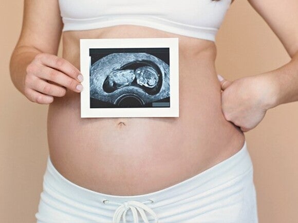 A pregnant woman holding her belly with food in front of her.