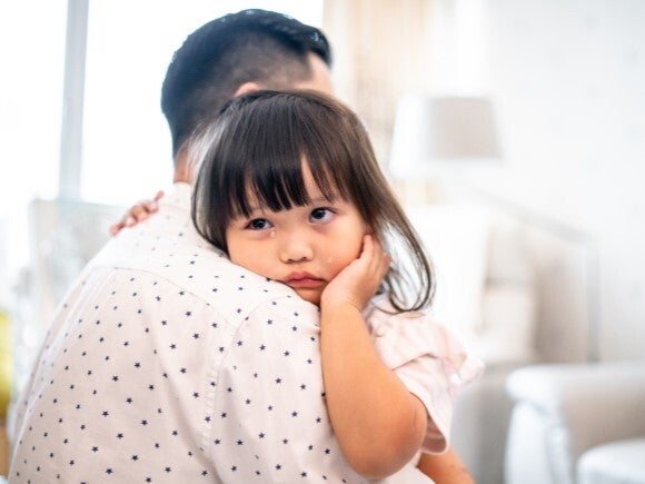 Toddler crying on her dads shoulder