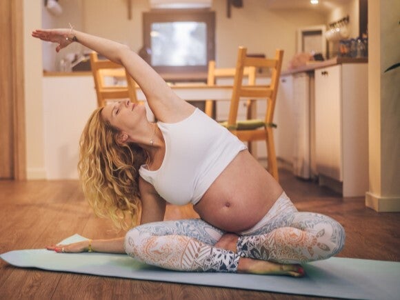 Pregnant woman doing yoga in her house