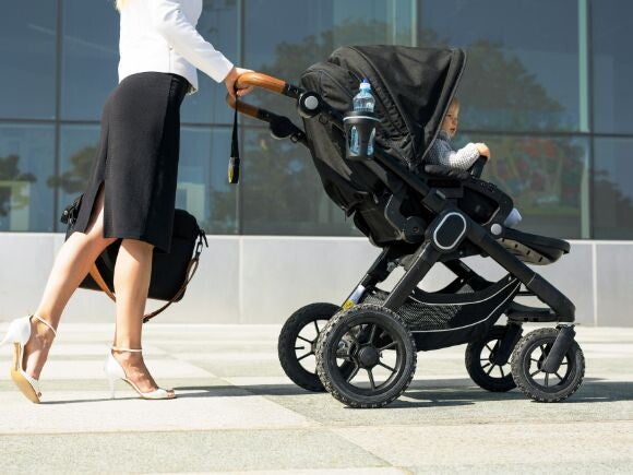 mother in business attire walking to work with her baby in a pram