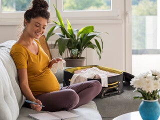 Pregnant woman packing her hospital bag using a list