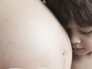 Child resting his head on his mother's baby bump.