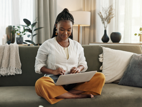 Woman in white shirt using her laptop on the couch