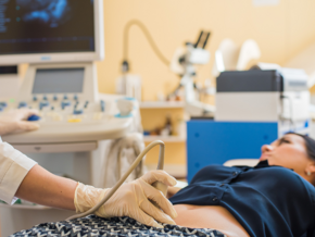 woman laying on doctors bed and doctor assessing her stomach