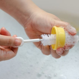 Woman cleaning bottle in sink