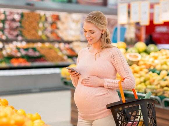 Pregnant woman grocery shopping in the produce section