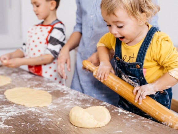 toddlers rolling out dough in the kitchen to cook