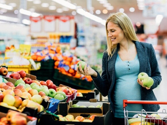 Pregnant woman selecting fresh apples.
