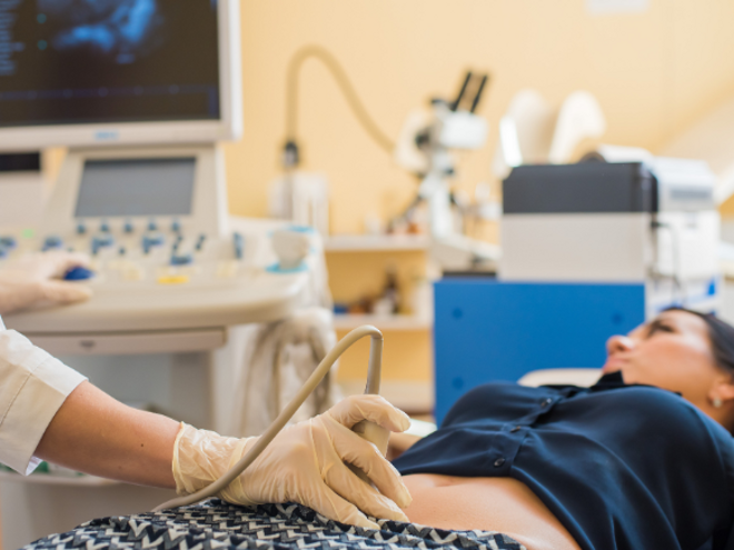 woman laying on doctors bed and doctor assessing her stomach