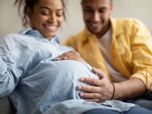 Pregnant woman and her partner holding her pregnant belly