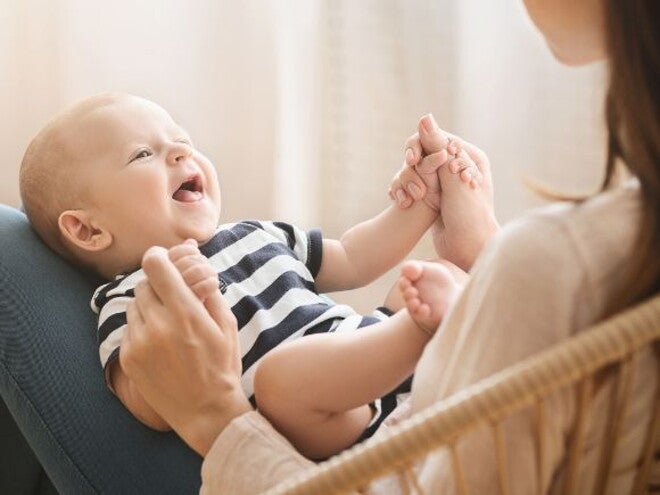 Baby on mothers lap holding mothers hand