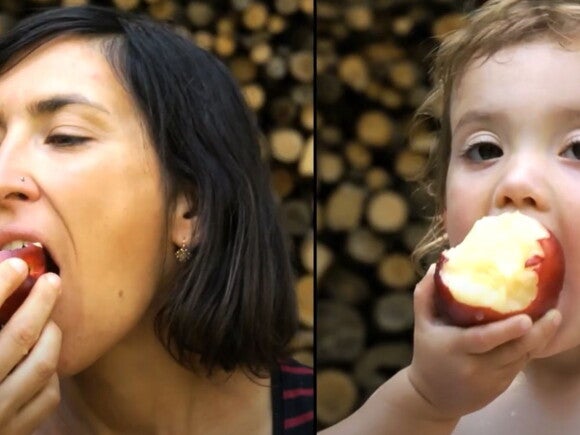 Mother and toddler eating an apple the same way