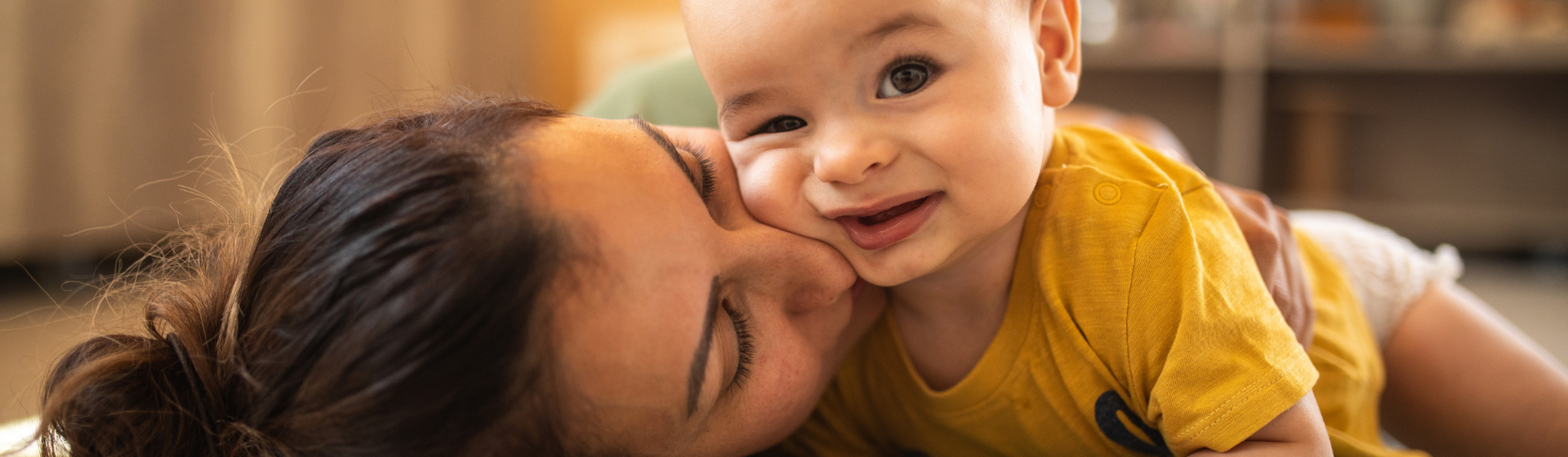 Mother and baby in yellow onesie playing together