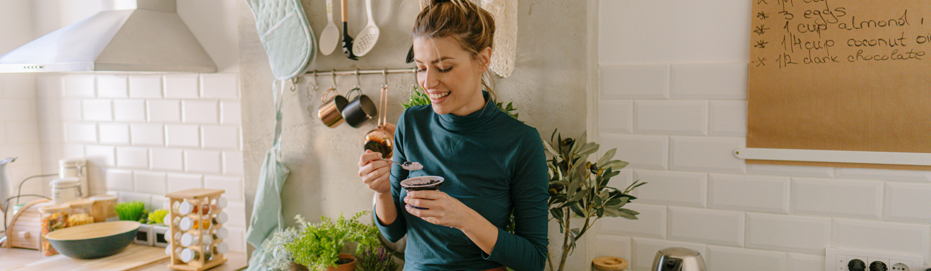 Woman in green shirt eating food in her kitchen