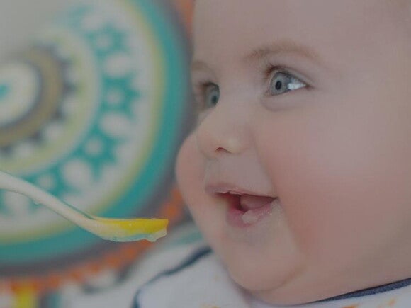 Baby eating infant cereal off a baby spoon