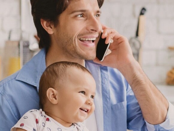 father talking on phone holding baby