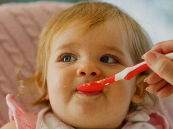 child being fed food from spoon