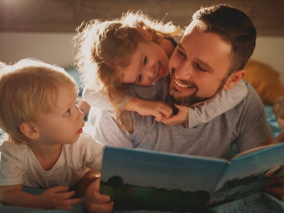 father reading book to two toddlers