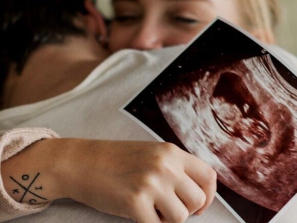 man and woman hugging and holding sonogram image