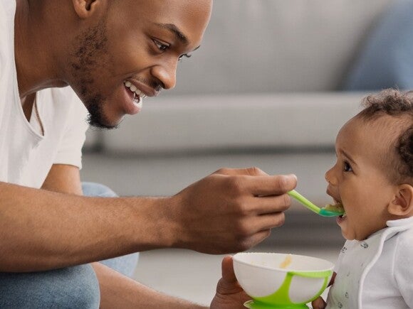 man feeding his child with a spoon