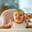 young baby eating solid food from spoon